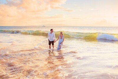 Couple holds hands and walks on the beach in Wailea photographed by Love + Water during their Maui babymoon