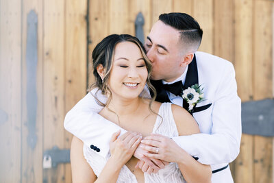groom kissing bride on cheek at evanelle vineyard fresno wedding venue