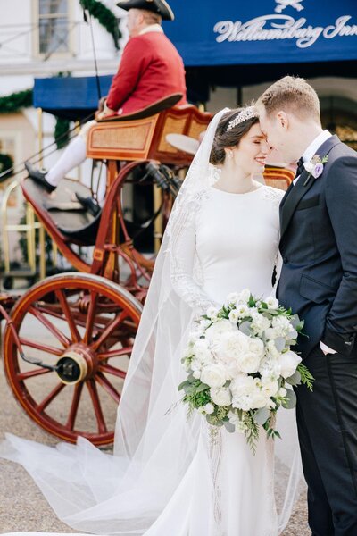 bride and groom embrace in front of a colonial carriage at Williamsburg Inn.