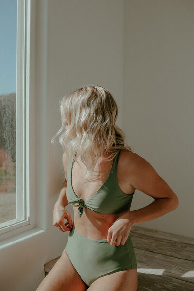 girl posing by window in green high waisted bikini