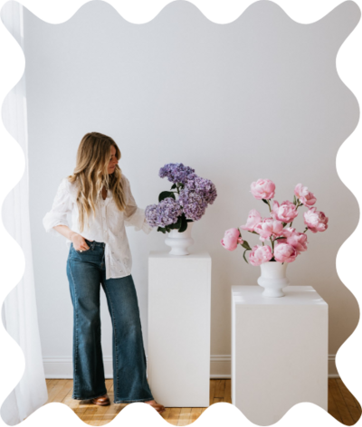 Saratoga Springs, NY florist standing next to white pedestals with purple hydrangeas and pink peonies