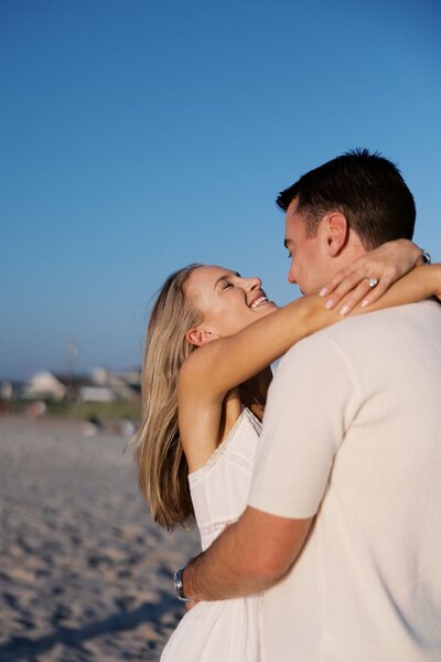 Couple hugging and smiling in the golden light on the beach at Southampton