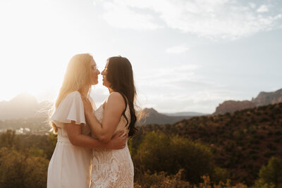 Groom kisses bride on the cheek in the desert near sunset