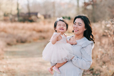 A filipina mom holder her one year old daughter enjoying their Northern virginia family photography