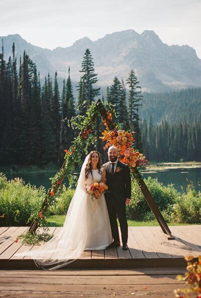 bride and groom embrace on the rocks by the ocean on their wedding day