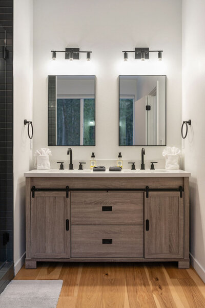Modern bathroom with double vanity, two mirrors, and black fixtures