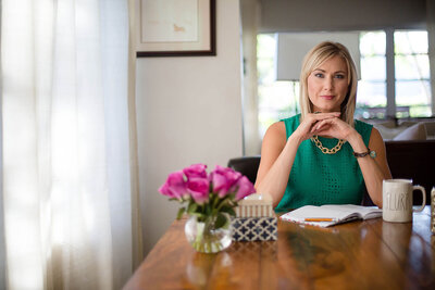 Portrait of Blonde woman wearing a green top at a table looking into camera at Tiny House Photo in Albany New York