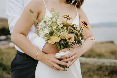 bride and groom embracing holding flowers