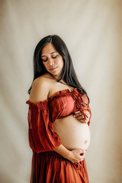 studio maternity photo of mom in red two piece maternity dress