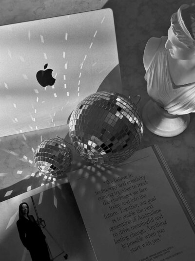 Disco balls reflecting light beside a laptop and statue – Brand Identity Elevation