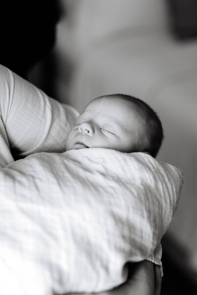 Black and white close up portrait of newborn wrapped in blanket