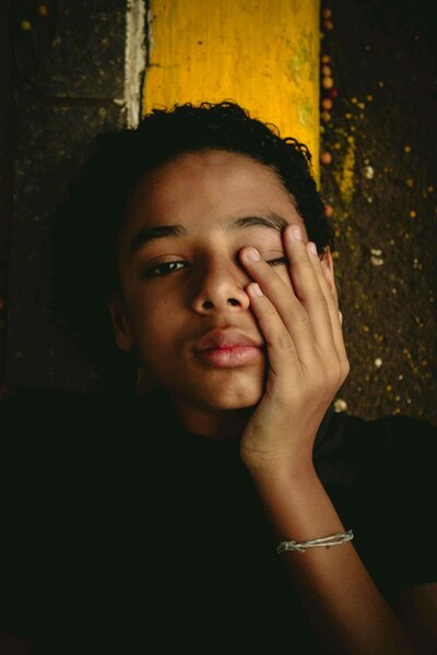 black boy sad in front of yellow wall
