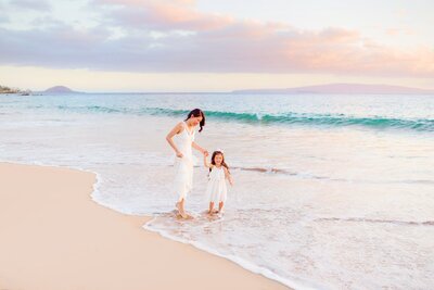 mother and daughter holding hands and laughing at a south maui beach