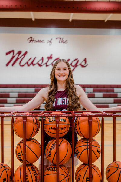 Girl basketball player poses for the camera in high school gym.
