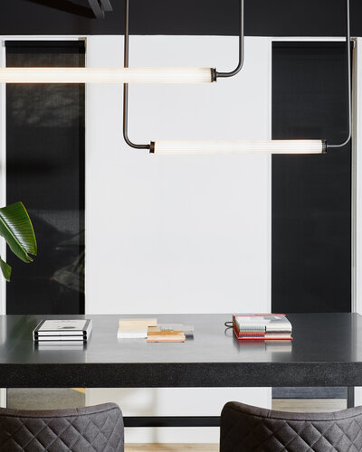 Two bar light fixtures hanging over a black table covered in various books