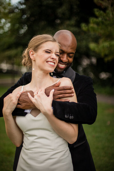 interracial couple bride and groom hugging