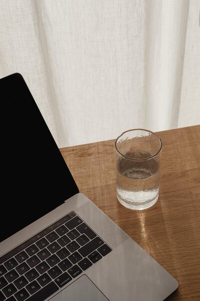 EIn Glas Wasser neben einem Macbook