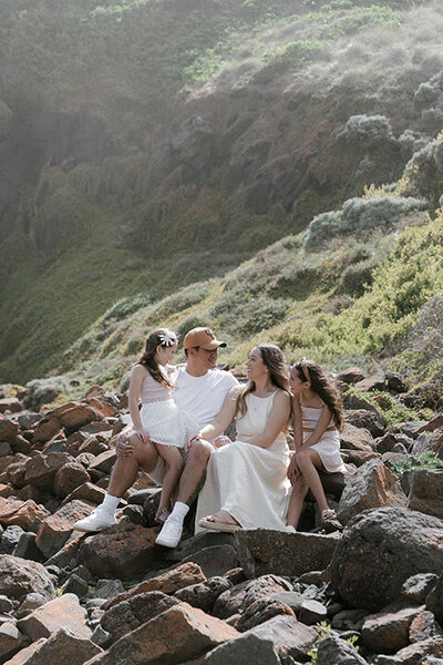 Portrait photography of a happy family sitting on rocks by Ada and Ivy photography