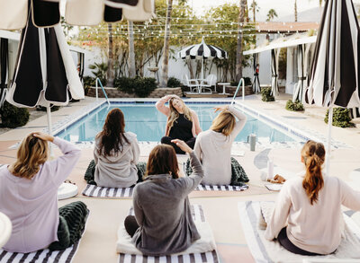 group of women in yoga class outside in palm springs poolside