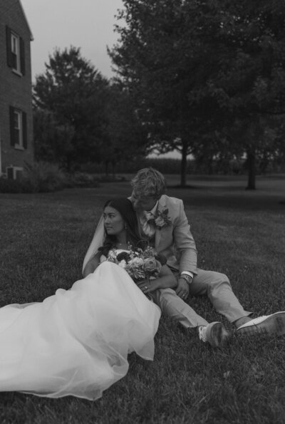 Bride and groom enjoying their elopement wedding while sitting in the grass