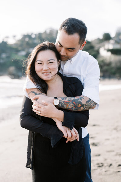 bay area photographers photographs engagement pictures with man and woman kissing with man holding the woman's chin while they are on the beach