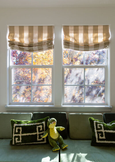 Custom striped window covering in playroom above a green seating area.