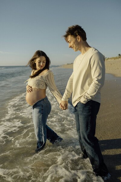 couple holds hands and walks into the ocean