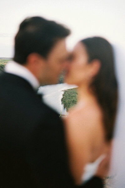 Bride and groom sharing a blurred, romantic kiss with the Chavón River landscape softly in focus — captured on film by Asia Pimentel Photography.