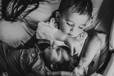 big brother holding his newborn sister for the first time, showcasing a heartwarming moment during a fresh 48 hospital photo session.