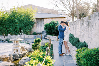 Landscape photo of couple standing close with their heads touching with the sun shining behind them