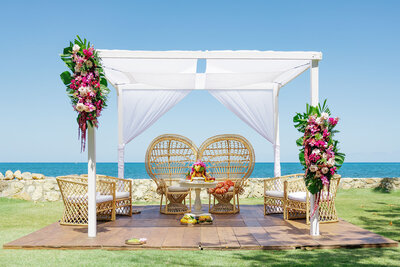 Two chairs sitting on a small covering next to the ocean 