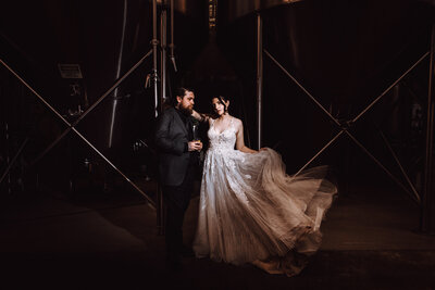 A bride and groom strike a dramatic pose in a dark space lit by a spotlight of off camera flash