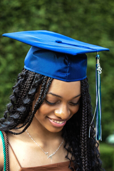 Senior girl wearing a black Paul Mitchell The School shirt and blue jeans holding hair in a gazebo