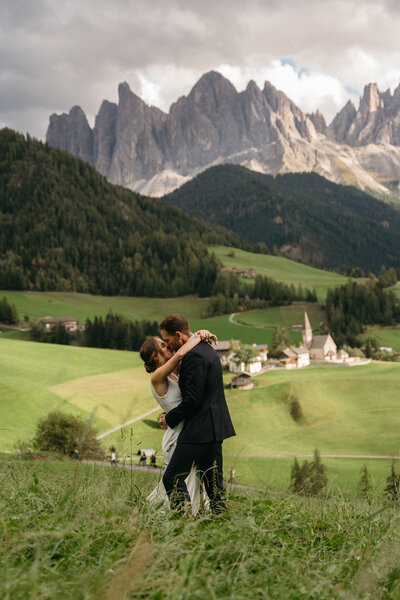 Couple eloping in a field in Val di Funes, the Dolomites