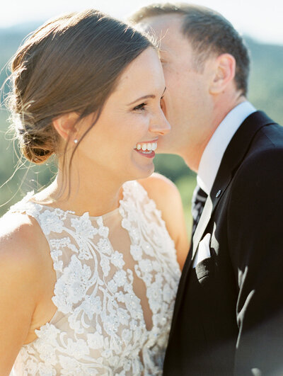 groom whispering something in bride's ear that makes her laugh