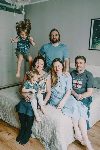 family of six sitting on bed and smiling