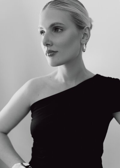 Thoughtful profile image of Yana in a black off-shoulder outfit and updo, representing her timeless and elevated bridal aesthetic in Northern California.