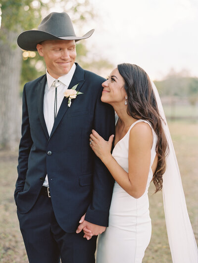 Bride smiling at groom wearing a cowboy hat