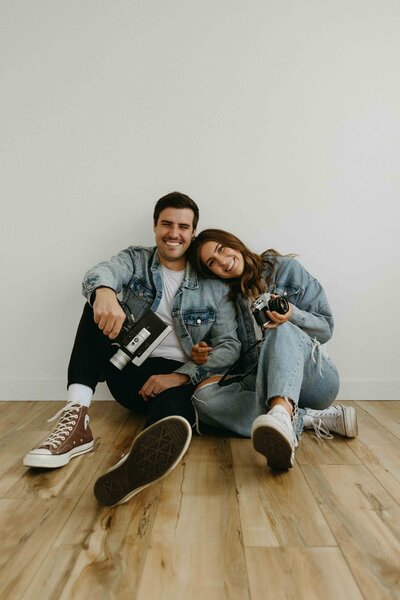 Close-up of Alberta photographer and videographer duo Hannah and Tyler posing for a photo with their camera and Super 8 recorder.
