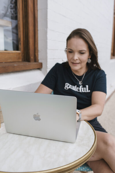 Emily May sitting at her Apple Mac computer