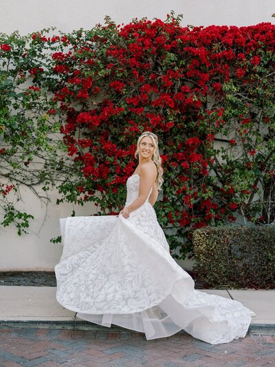 bride holding an moving dress in front of red flowers to show wedding planners in southern new jersey