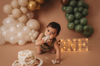 Cake smash milestone session with Atlanta, Georgia cake smash photographer. Milestone photography session with earthy tones, balloon garland and sweet baby boy eating cake for his first birthday.