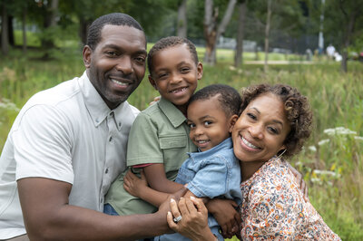 Two parents smiling with their kids hugging in between them 