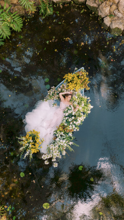 Bride floats in a boat surrounding by flowers