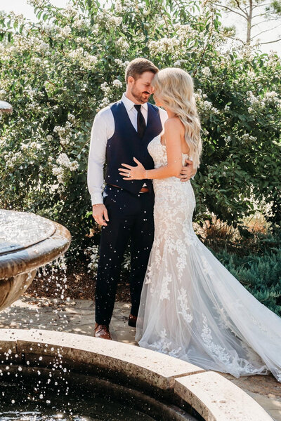 Bride and groom holding each other near water fountain