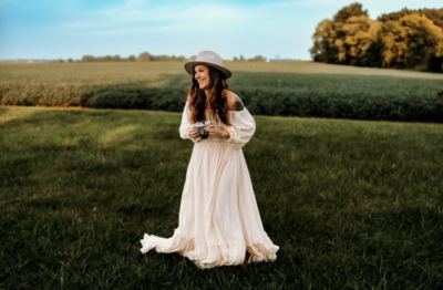 woman standing in a field with a camera