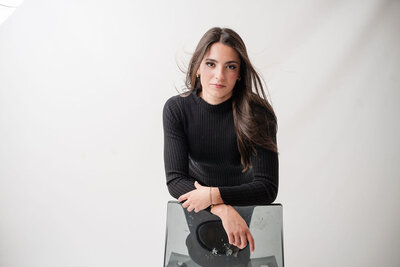 Senior girl sitting on a short wall, in a tulle dress and necklace