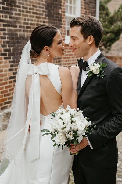 a bride and groom in classic looks with bow dress