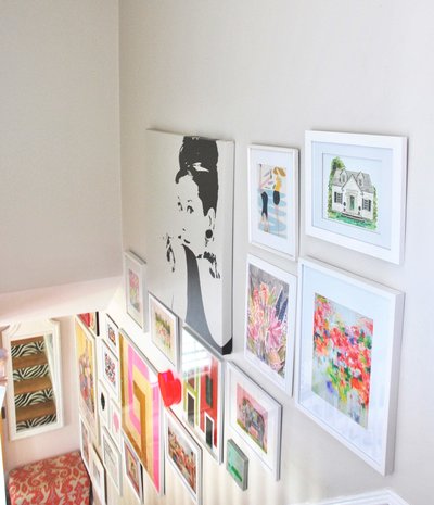 A gallery wall of framed fine art along a staircase wall.