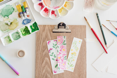 watercolor bookmarks with paint around it on a desk